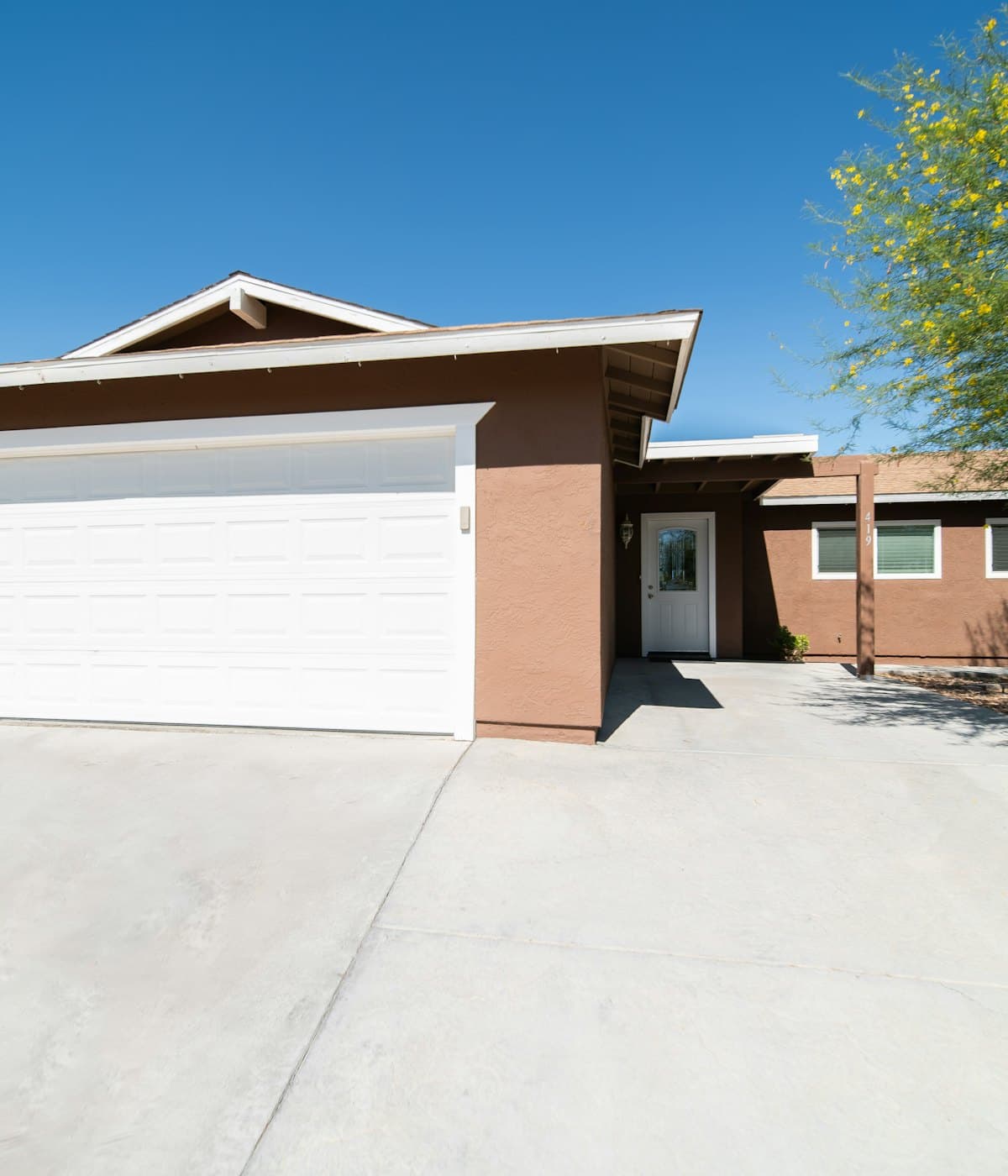 A single-storey home with a wide concrete driveway sweeping up to the garage