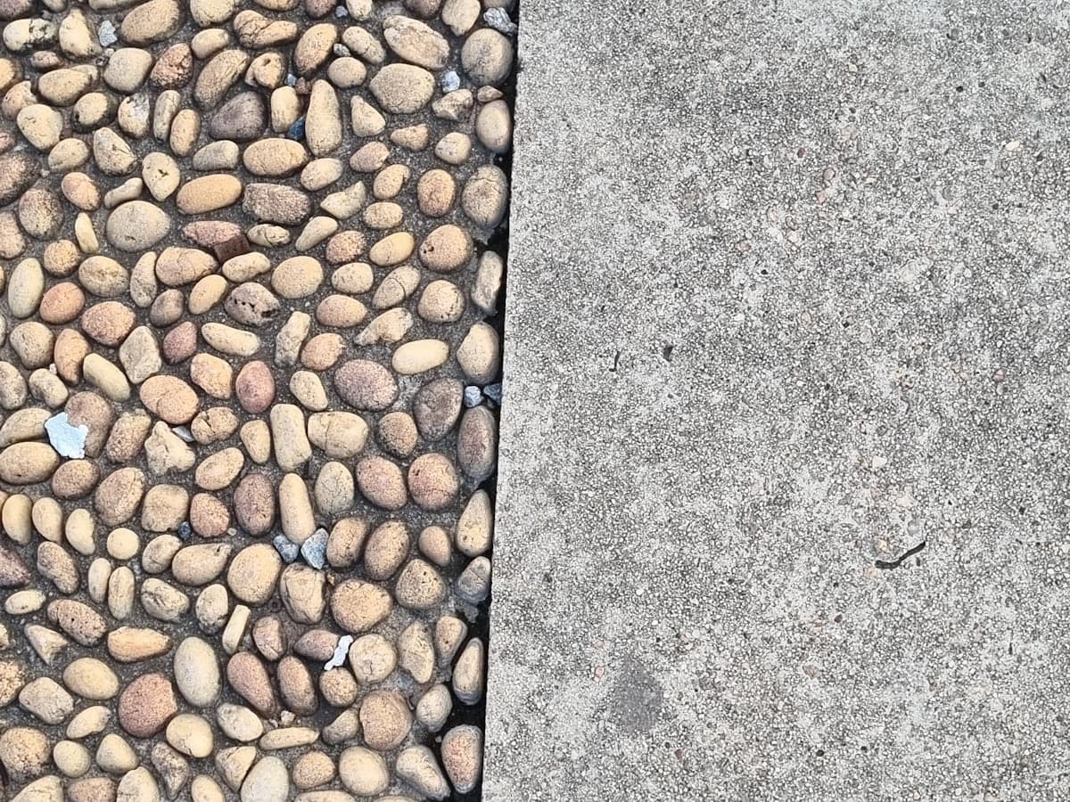 A concrete edge meeting a drainage bed of loose stone