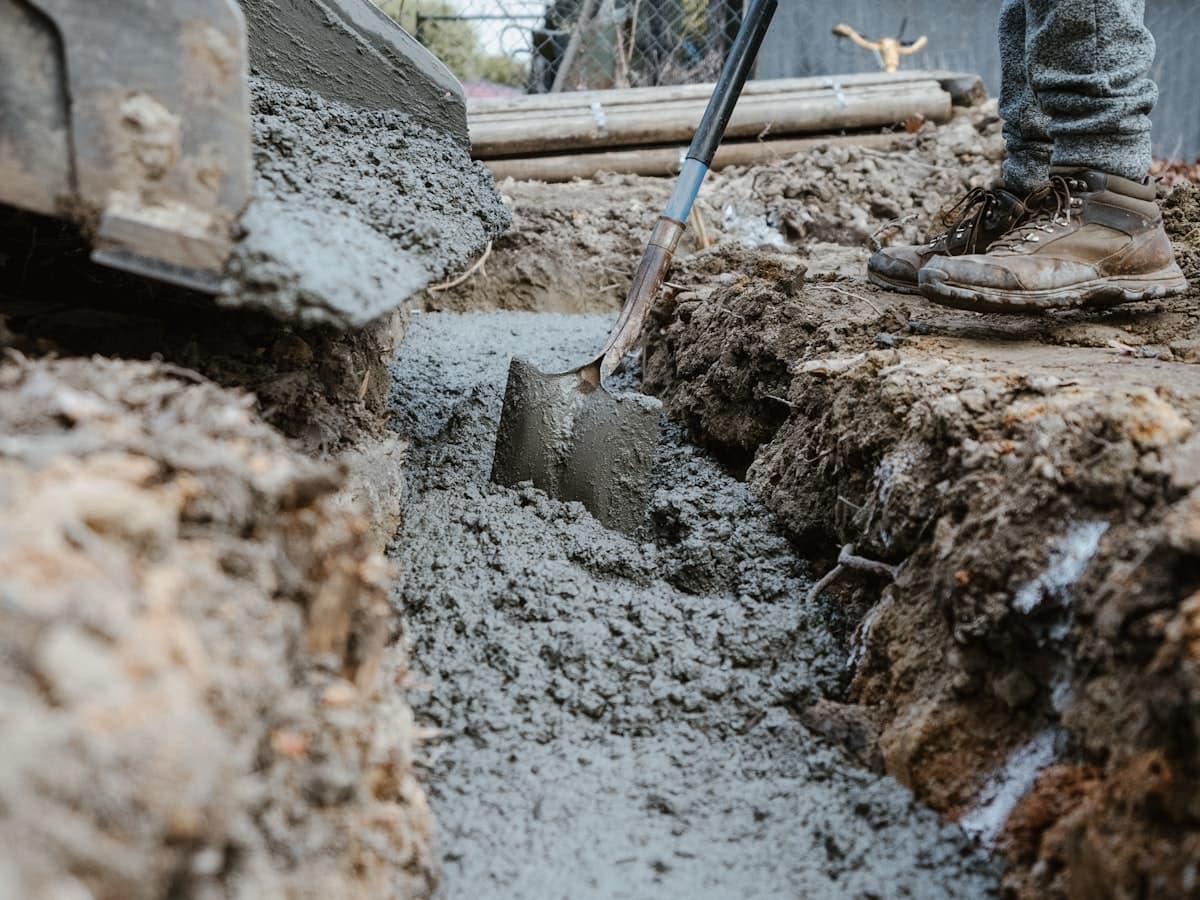 Wet concrete being worked into an excavated trench