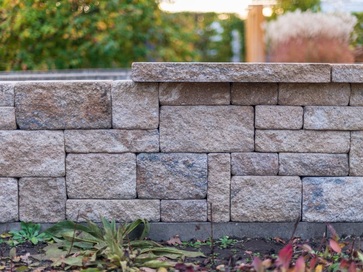 A capped block retaining wall alongside a planting bed